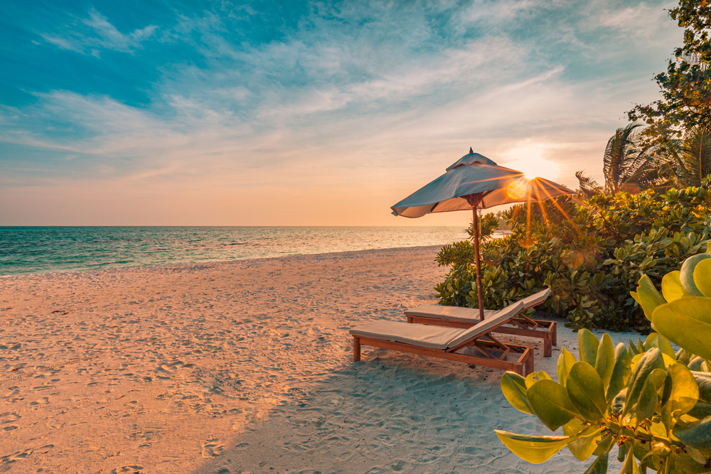 Luxury beach resort, beach loungers near the sea with white sand over sea Topical island background, summer vacation concept, holiday and tourism design. Exotic landscape, inspirational leisure banner