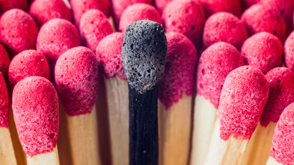 One burnt match surrounded by many pink unburnt matches to indicate burnout.
